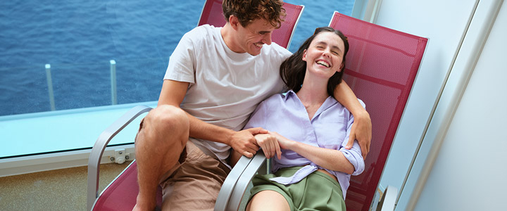 Junges Paar genießt ausgelassen die Zeit zu zweit auf ihrem privatem Balkon an Bord der AIDAmar.