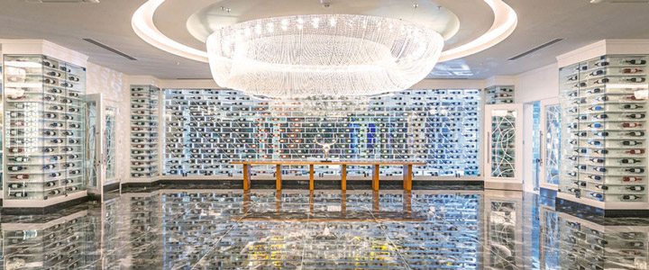 Ein eleganter Weinkeller als Showroom mit unzähligen Weinflaschen hinter Glas. Der lichtdurchflutete Raum beeindruckt, ein spektakulärer Kronleuchter setzt strahlende Akzente.