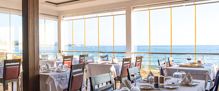 Im Gastrobereich auf der Terrasse sind die Tische gemütlich eingedeckt und schaffen eine entspannte Atmosphäre, während der Blick ruhig über das Meer gleitet.